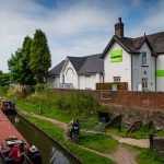 People on barge going along canal next to Tamworth Co-op store. Example of commercial photography by Enigma Communications.