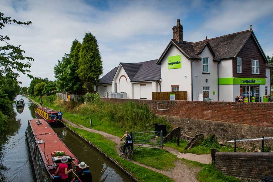 People on barge going along canal next to Tamworth Co-op store. Example of commercial photography by Enigma Communications.