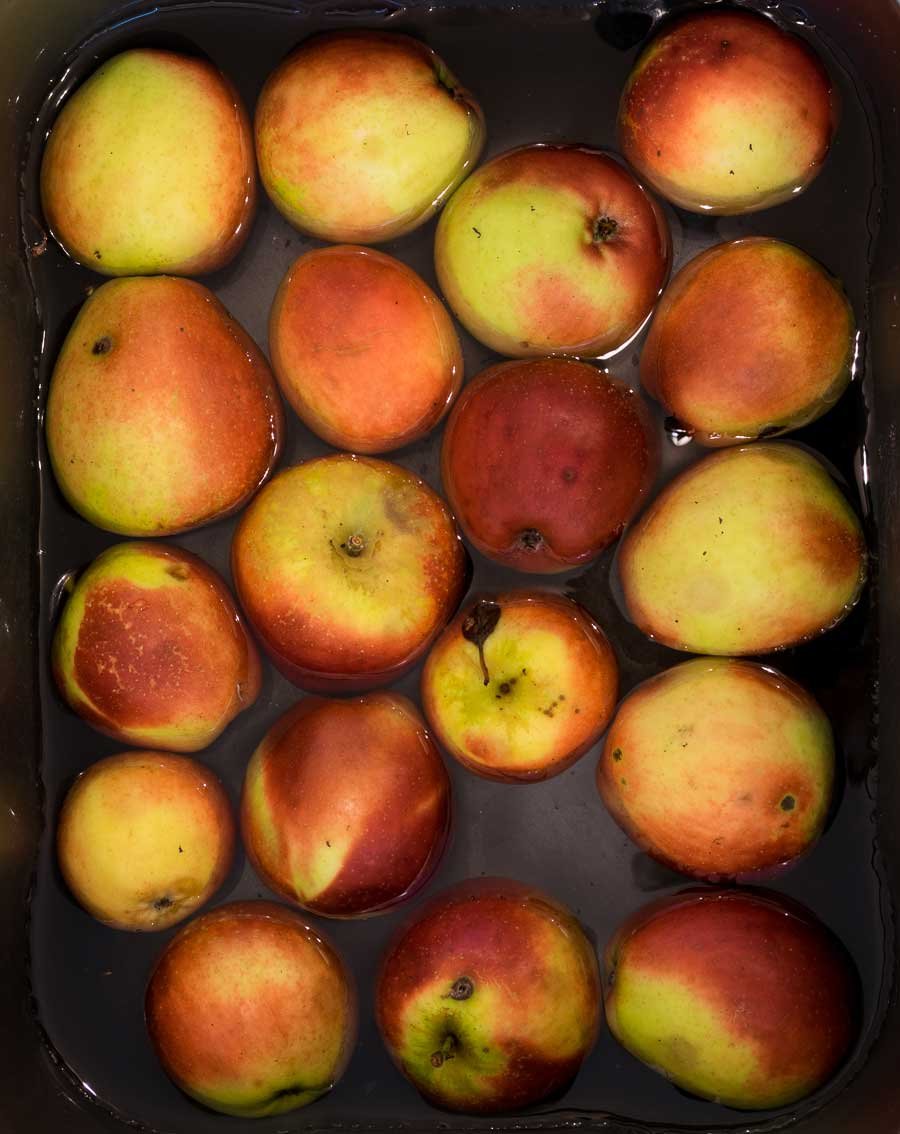 A bowl of red and yellow apples in a bowl of water, seen from above.