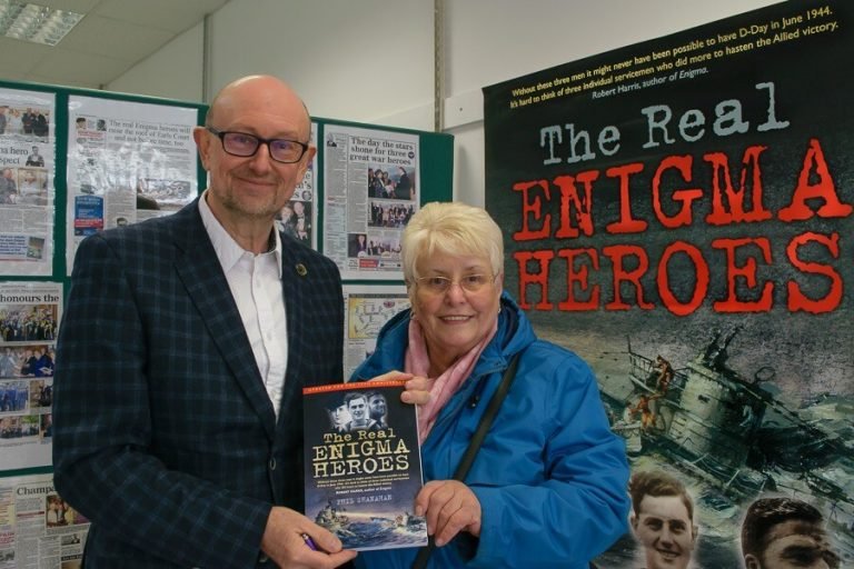 Phil Shanahan holding his book, The Real Enigma Heroes, with Carol Bridges, cousin of Colin Grazier, at exhibition.